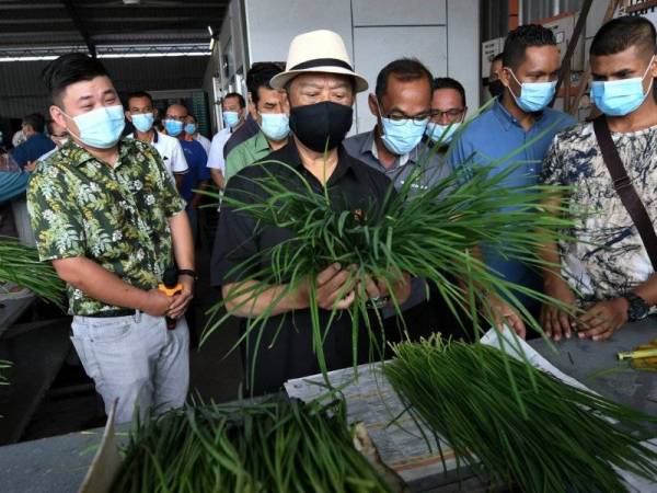 Muhyiddin (dua dari kiri) menunjukkan daun kucai semasa mengadakan lawatan di Pusat Pengumpulan dan Pemprosesan Perladangan Berkelompok Batu 18 dan Batu 19 Sengkang 1 Grisek hari ini. - Foto Bernama
