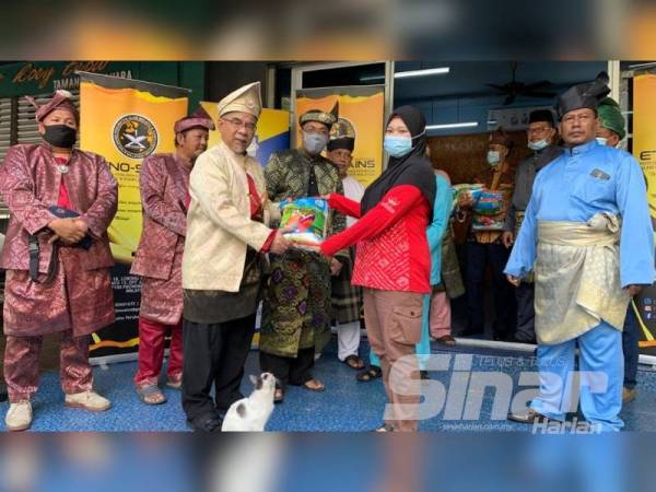 Baharudin (empat, kiri) mengiringi Supyan ketika menyerahkan bantuan kepada keluarga terpilih di sini.
