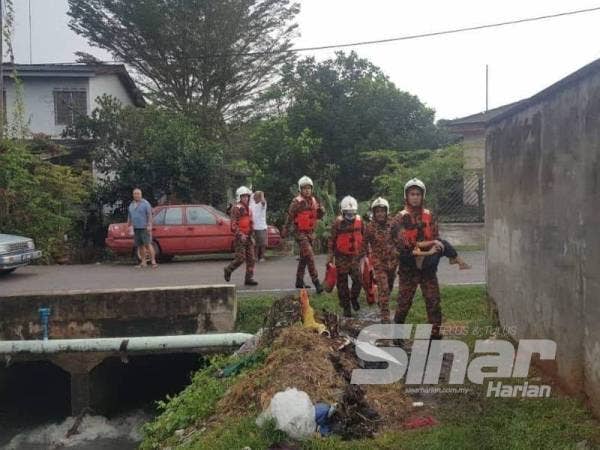 Anggota bomba menyelamatkan Mohd Akif yang dihanyutkan dalam parit di Taman Tangkak Jaya, Tangkak hari ini.