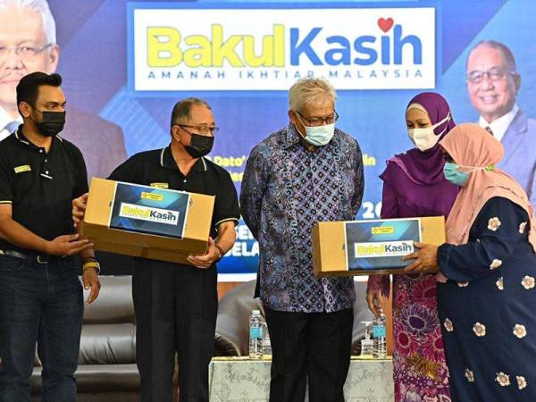 Menteri Dalam Negeri, Datuk Seri Hamzah Zainudin (tiga dari kiri) menyerahkan sumbangan kepada Sahabat AIM, sambil disaksikan oleh Lajim (dua dari kiri) dan Pengarah Urusan AIM, Mohamed Shamir Abdul Aziz, dalam program Bakul Kasih AIM di Dewan Felcra Seri Gala, Slim River.