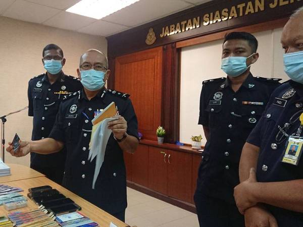 Shahrul Lalli menunjukkan kad bank dan dokumen pinjaman wang pada sidang akhbar di Ibu Pejabat Kontinjen Polis (IPK) Melaka di Bukit Beruang di sini hari ini.