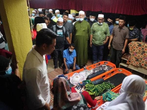 Muhammad Alhafiz Mohamad, 29, (duduk) menatap sedih Bapa ketiga-tiga jenazah anaknya sebelum dikebumikan di Tanah Perkuburan Islam Kampung Sungai Putat, Batu Berendam, Melaka tadi.