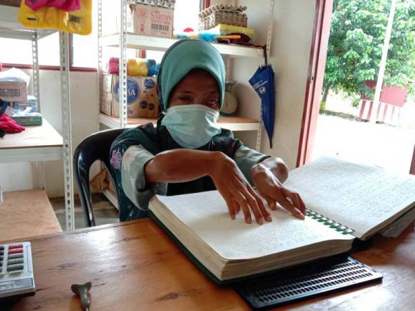 Noor Ashikin membaca Al-Quran bagi mengisi masa lapang ketika berada di kedai runcit.