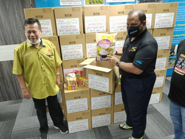 Ramli (dua dari kiri) menunjukkan antara barangan asas yang terdapat dalam kotak infak yang disumbangkan kepada mereka yang memerlukan.