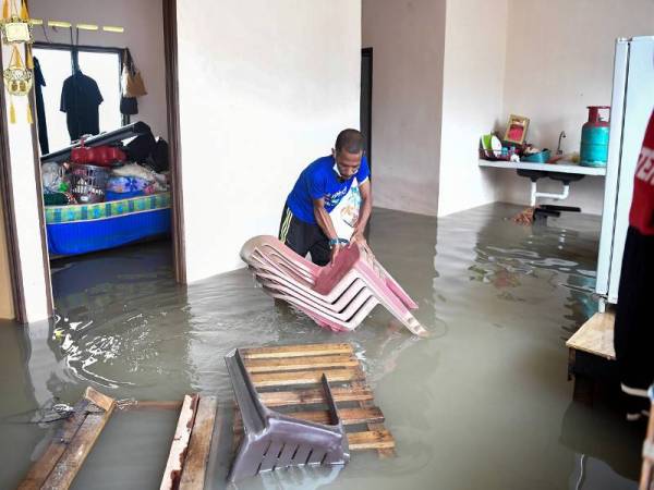 Mangsa banjir Mohd Azlan Samsudin, 37, mengangkat kerusi selepas rumahnya ditenggelami banjir ketika tinjauan di Program Perumahan Rakyat Termiskin (PPRT) Kampung Baru Kemasik, hari ini.- Foto Bernama