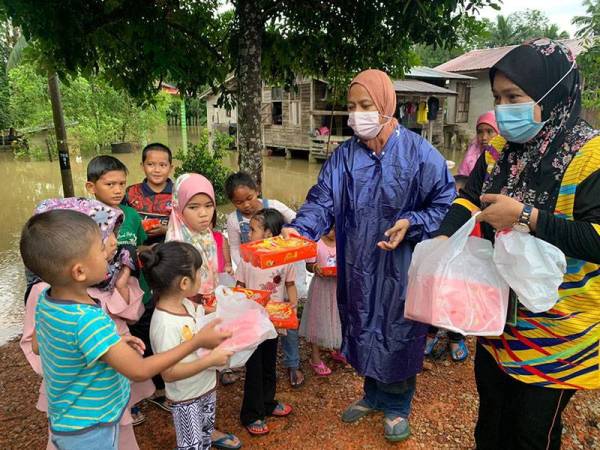 Tuan Zaimah (kanan) menyampaikan sumbangan piza percuma kepada mereka yang terjejas akibat banjir di sekitar kawasan Rantau Panjang.
