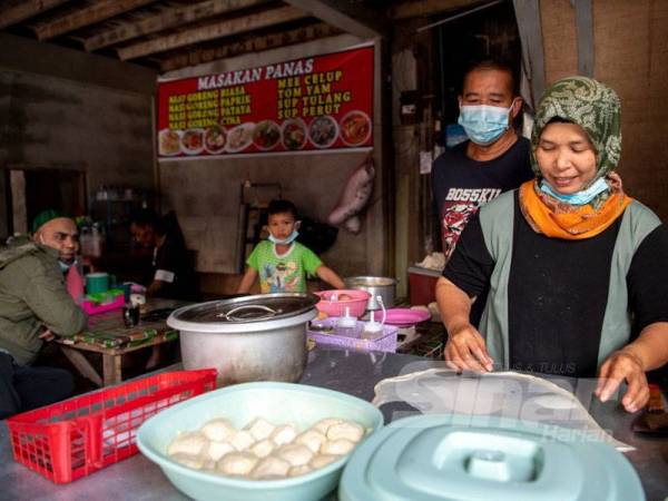 Umi Kalsom Yakub (kanan) dan suaminya, Mohd Fadhli membantu antara satu sama lain dalam menyediakan makanan untuk pelanggan mereka,
