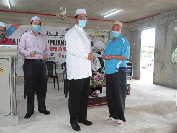 Ahmad Marzuk (tengah) menyerahkan bantuan makanan berikutan musim tengkujuh kepada penerima di DUN Panchor, di sini hari ini.