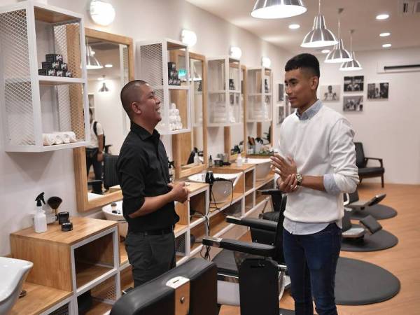 Hafizh Syahrin (kanan) mendengar sesuatu yang diperkatakan oleh Ketua Pegawai Eksekutif Nimroc Holdings Sdn Bhd, Ardy Damis (kiri) pada majlis pembukaan kedai francais gunting rambut miliknya Nimroc Barbershop di Ampang pada Ahad.- Foto Bernama