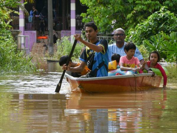 Mohd Fikri Ngah, 37, (kiri) bersama bapa saudara Mohd Nor Zainuddin, 49, serta anak saudaranya menaiki sampan untuk ke jalan utama selepas rumah mereka dinaiki air ketika tinjauan di Kampung Bukit Mentok hari ini. - Foto Bernama