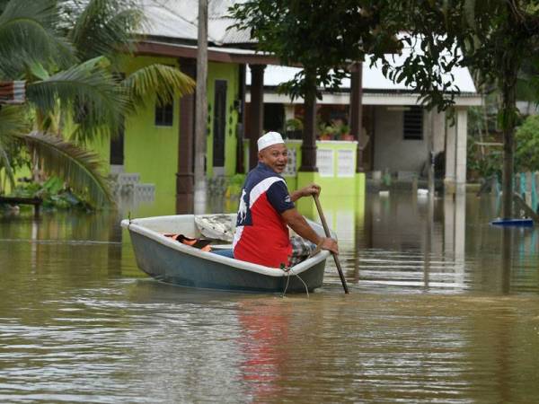Wan Zakaria Wan Tawang, 60, mengharungi banjir dengan menaiki sampan ketika tinjaua di Kampung Tanjong, Bukit Mentok hari ini. - Foto Bernama