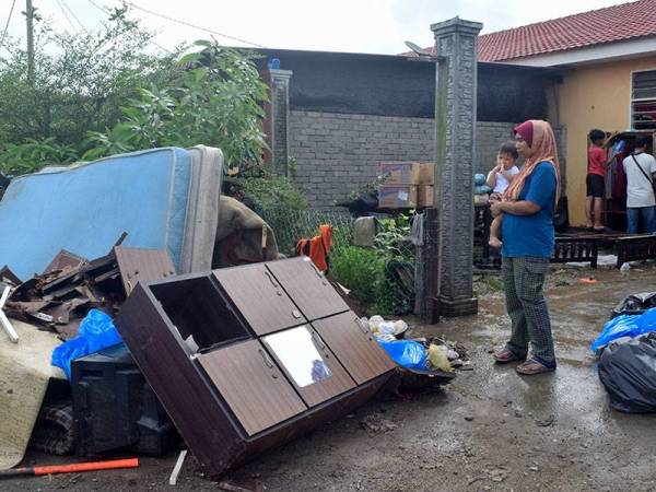 Ruzaida Ismail, 38, (kiri) melihat barangan dalam rumahnya yang rosak selepas kediamannya dilanda banjir ketika tinjauan di Perumahan Rakyat Teluk Kalong hari ini.