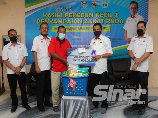 Zulkiffli (tengah) yang mewakili penerima bantuan zakat asnaf mualaf Kampung Orang Asli Panchor menerima replika cek berjumlah RM11,000 yang disampaikan Mohd Salim (dua dari kanan) di Jempol baru-baru ini.