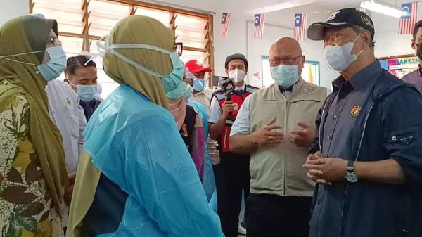 Muhyiddin (kanan) beramah mesra dengan kakitangan kesihatan yang bertugas di PPS SK Gual Tinggi ditemani Dr Aminuddin (dua dari kanan).