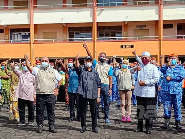 Muhyiddin (tiga dari kanan) dan Aminuddin (empat dari kanan) bergambar bersama kepimpinan tertinggi Kelantan dan petugas di PPS SK Gual Tinggi, Rantau Panjang.