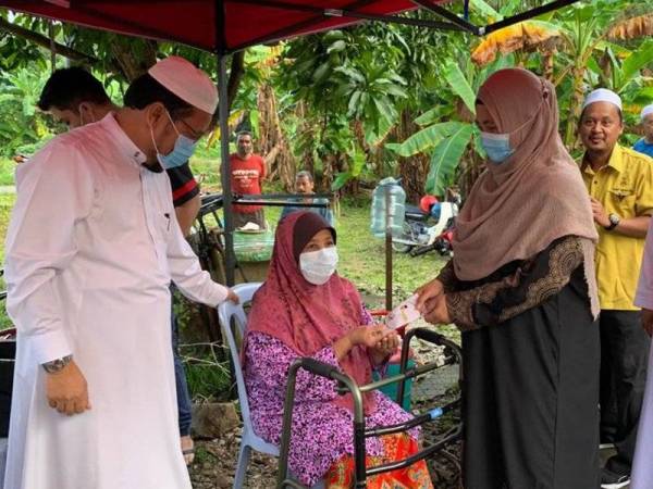 Che Abdullah (kiri) bersama isteri, Datin Saleha Yaacob dan Mohd Rusli (kanan) ketika menyampaikan sumbangan kepada Mek Mas Hamat,67, yang uzur sempena program Santai Peladang pada Ahad.