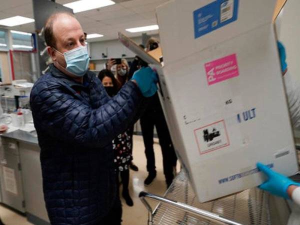 Gabenor Colorado, Jared Polis membantu meletakkan vaksin Covid-19 pertama di negeri itu dalam peti di makmal jabatan kesihatan negeri. Foto AP