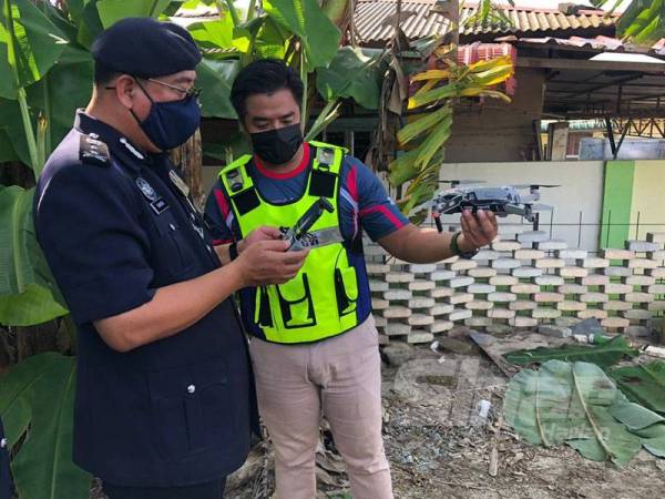 Ketua Polis Kelantan, Datuk Shafien Mamat (kiri) yang mengawal dron bagi meninjau situasi semasa pergerakan penghuni di penempatan mereka melalui udara di lokasi Kluster Halban, Melor, Kota Bharu.