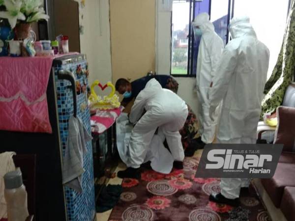 Anggota bomba yang lengkap berpakaian PPE mengangkat mayat mangsa.