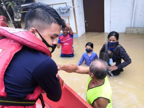 Anggota bomba memindahkan mangsa banjir di Kampung Laut, Batu 10, Skudai, Johor Bahru selepas kediaman mereka dinaiki air pada Jumaat.