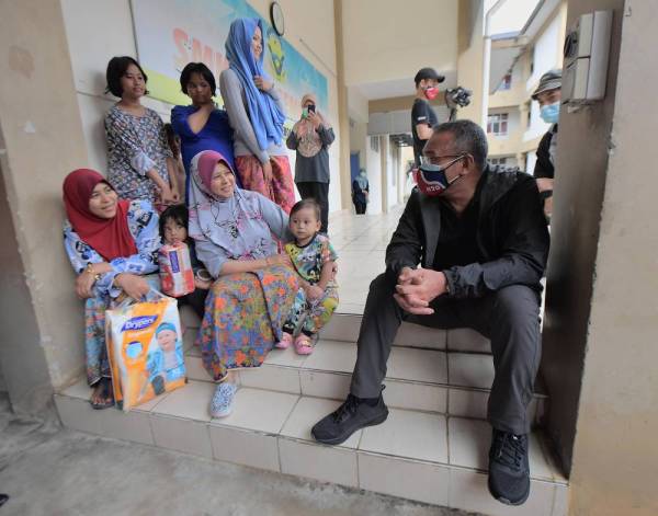Hishammuddin beramah mesra dengan mangsa yang terkandas selepas jalan Kluang - Mersing terputus dilanda banjir ketika melawat ke PPS di Sekolah Menengah Kebangsaan Seri Sembrong, Kluang pada Ahad. -Foto Bernama