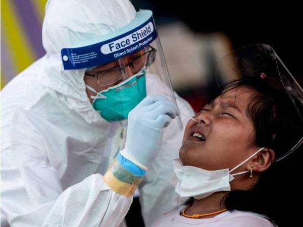 Pegawai perubatan melakukan ujian swab ke atas kanak-kanak perempuan di pasar makanan laut di Samut Sakhon.