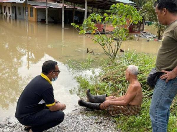 Zainol Fadzi (kiri) bertemu dengan salah seorang mangsa banjir ketika meninjau kawasan yang terjejas di sekitar DUN Sungai Manik pada Isnin.