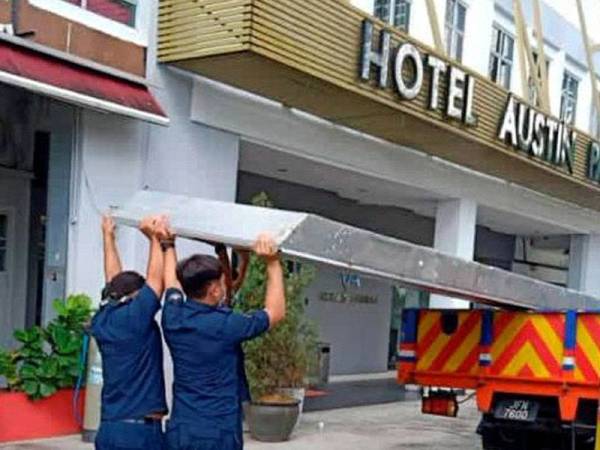 Penguat kuasa MBJB menurunkan papan iklan yang mengandungi unsur komunis di sebuah premis makanan di Taman Mount Austin, Johor Bahru pada Isnin.