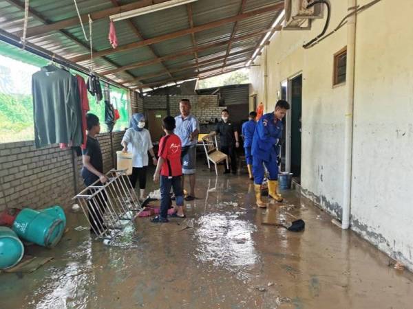 Anggota Angkatan Pertahanan Awam (APM) Segamat membantu membersihkan rumah penduduk yang terjejas akibat banjir di Kampung Seremin, Segamat pada Selasa.
