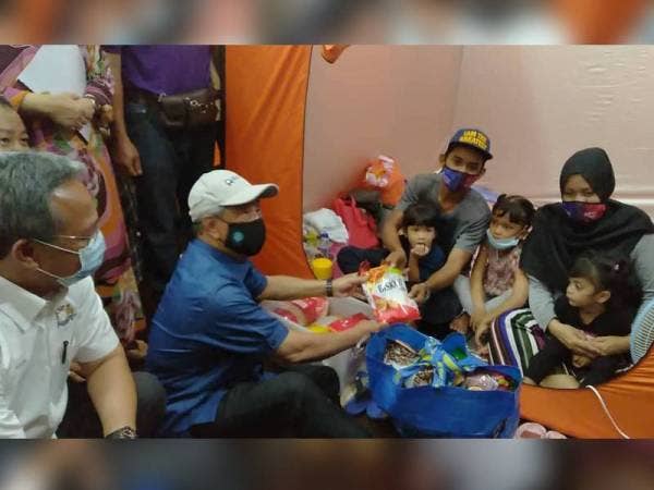 Muhyiddin (tengah) menghulurkan sumbangan kepada mangsa banjir di PPS Kolej Vokasional Kota Tinggi pada Selasa.