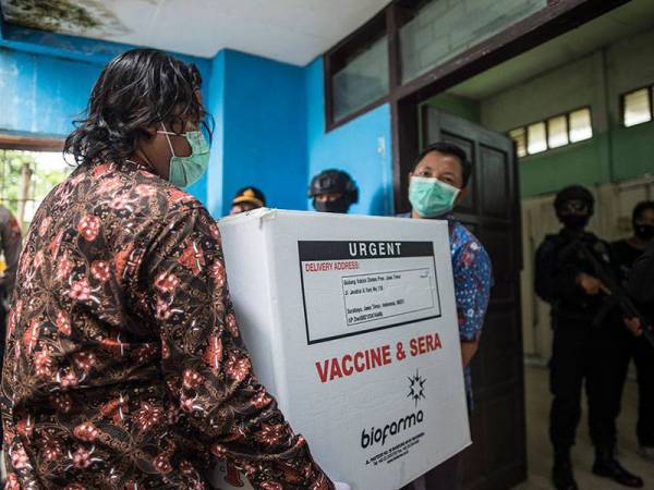 Bekalan vaksin mula diedarkan di Surabaya dan turut diiringi pihak berkuasa. - Foto: AFP