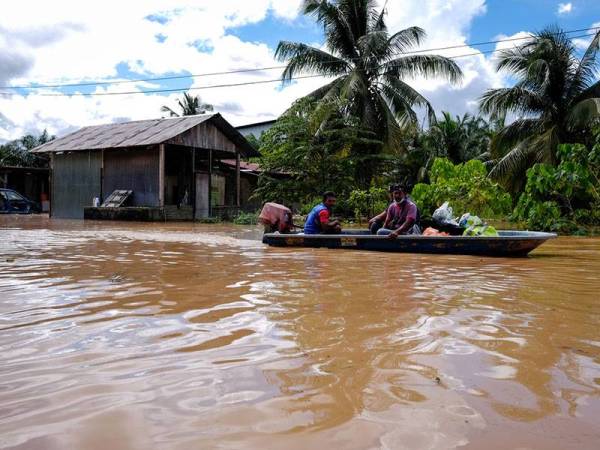 Beberapa penduduk menggunakan bot meredah banjir untuk mendapatkan bekalan makanan dan keperluan harian ketika tinjauan di sekitar kawasan Paya Garok hari ini. Foto Bernama