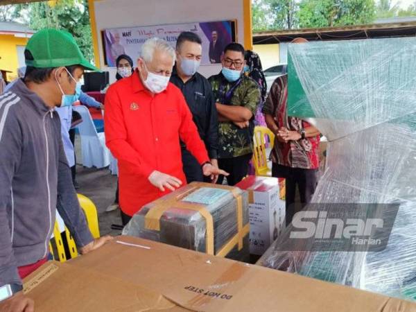 Kamarudin (dua darikiri) memeriksa barangan yang akan diterima oleh usahawan di bawah projek rezeki tani di PPK Cherang Rotan, Pasir Puteh
