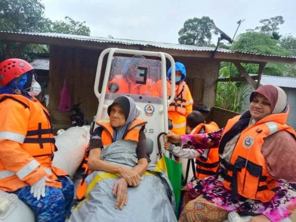 Anggota APM membawa mangsa banjir untuk dipindahkan berikutan beberapa kampung di Kuala Krai dinaiki air pada Khamis.