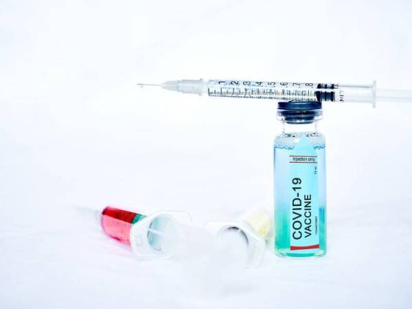 A syringe for injection with a coronavirus vaccine, antiviral tablets and 2 syringes with red and yellow liquids on a white background
