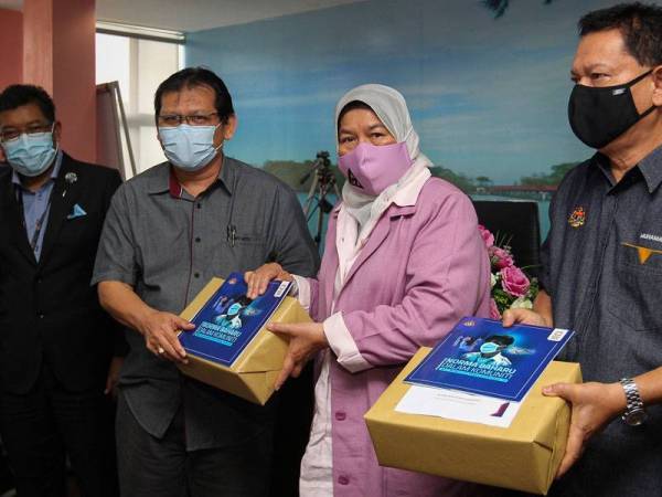 Zuraida (dua dari kanan) menyampaikan bungkusan pelitup muka kepada ahli Penggerak Komuniti Tempatan.