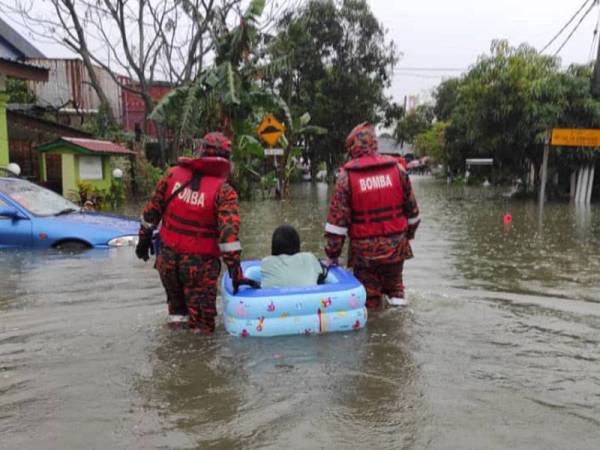 Anggota bomba membantu penduduk yang terjejas akibat banjir di Kampung Sri Jaya, Kota Tinggi iaitu antara penempatan yang masih dinaiki air sehingga hari ini.