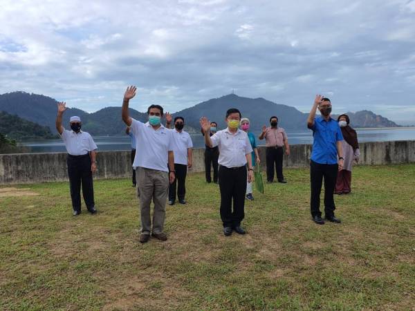 Kon Yeow (tengah) merakamkan gambar kenangan belatar belakang Empangan Mengkuang.