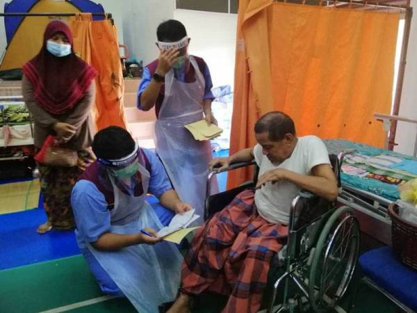 Husin (kanan) dirawat oleh petugas kesihatan sewaktu berada di pusat pemindahan sementara.