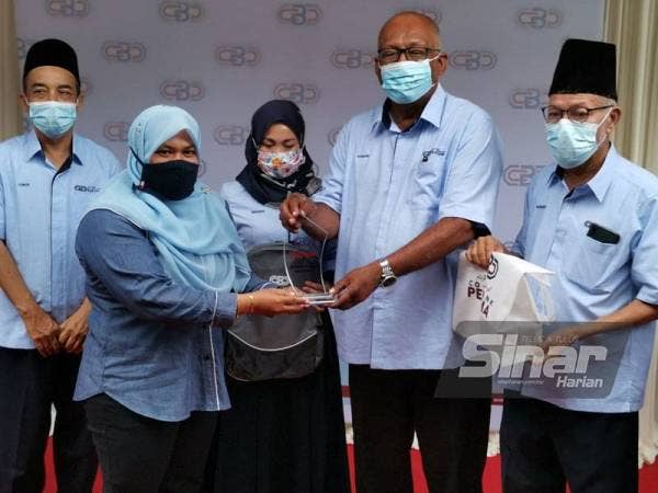 Kamari Zaman (dua dari kanan) menyampaikan bantuan persekolahan melalui program 'Back to School' kepada Guru Besar Sekolah Kebangsaan Bota Kiri, Farahdila Abu Seman.