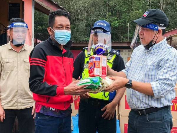 Ketua Jajahan Kuala Krai, Tengku Ab Rahman Tuan Yunus (kanan) menyampaikan sumbangan barangan keperluan kepada Mohd Rahim Mohd Yusof, 53 (dua dari kiri) sempena majlis Bantuan Misi Banjir McDonald’s Malaysia bersama Polis Diraja Malaysia (PDRM) Balai Polis Kuala Krai di Sekolah Kebangsaan Pemberian pada Sabtu. -- fotoBERNAMA