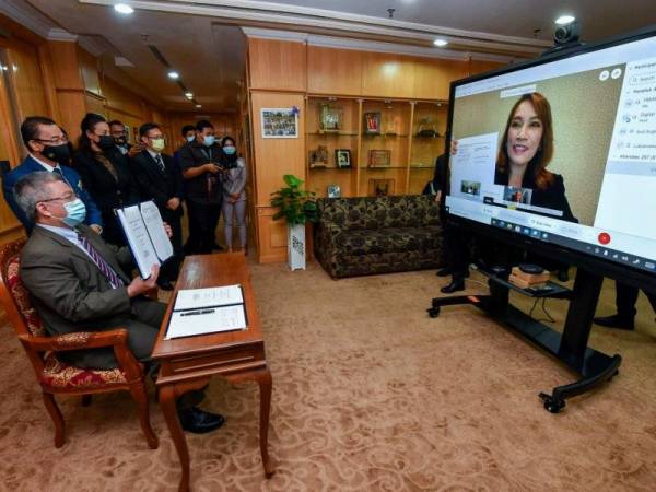 Menteri Kesihatan, Datuk Seri Dr Adham Baba yang mewakili kerajaan Malaysia dan Pengurus Negara Pfizer Malaysia dan Brunei, Luksanawan Thangpaibool menunjukkan dokumen perjanjian pembuatan dan pembekalan vaksin Pfizer Covid-19 selepas menandatanganinya melalui sidang video di Kementerian Kesihatan pada Isnin.
--fotoBERNAMA