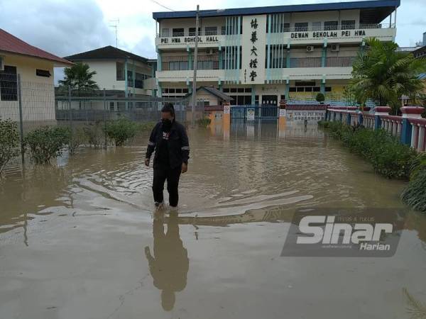 Asma berjalan keluar dari sekolah selepas membuat pemeriksaan di SJKC Pei Hwa yang turut dinaiki air pada pagi Isnin.