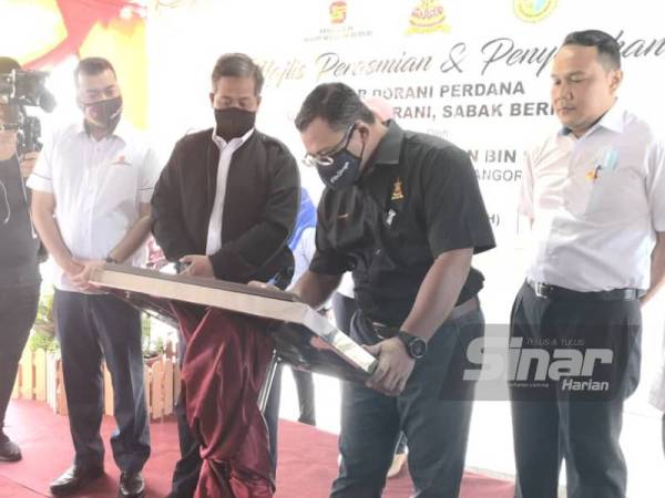Amirudin (dua dari kanan) menandatangani plak Perasmian Bazaar Dorani Perdana semasa lawatan kerja beliau di Sabak Bernam pada Isnin.
