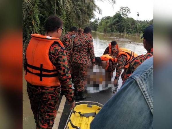 Anggota bomba mengangkat mayat Ikmal Hakimi selepas ditemukan terapung-apung selepas lemas dalam banjir di Kampung Bentong, Kluang, pada 4 Januari lalu.