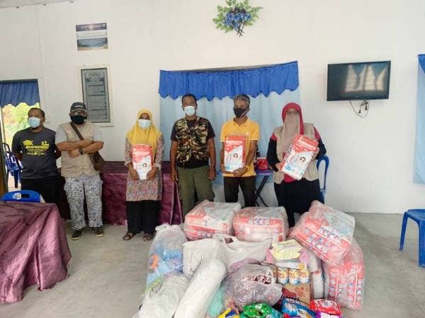 Intan Maziah (kanan) bersama produk dan barangan yang diagihkan kepada mangsa banjir di beberapa buah kampung di Ulu Tembeling
