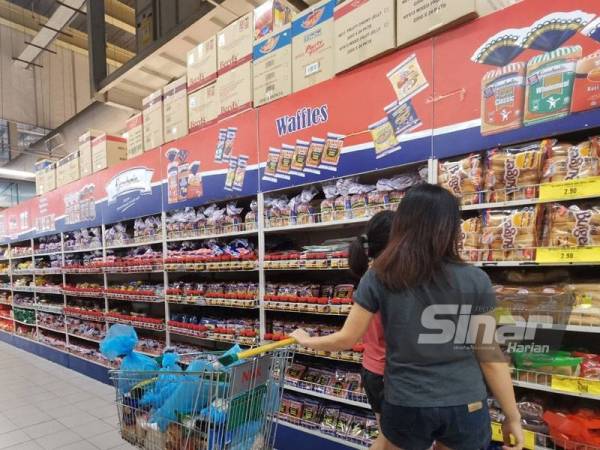 Kelihatan pelanggan memilih roti di sebuah pasar raya.