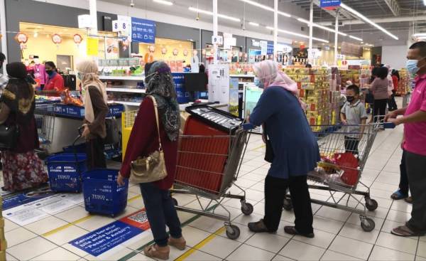 Orang ramai beratur di kaunter bayaran di sebuah pasar raya di sini.