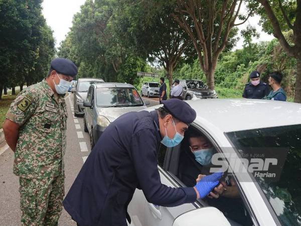 Abdul Majid (depan) melihat dokumen kebenaran salah seorang pemandu di SJR Jalan Taman Sutera Wangi, Batu Berendam, di sini, pada Rabu.