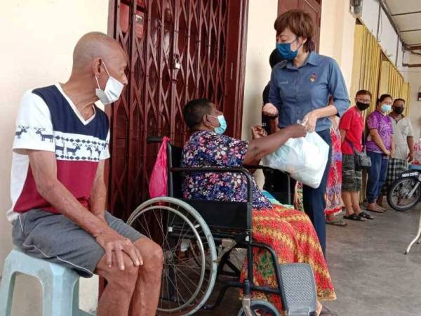 Nicole (tiga dari kiri) menyampaikan sumbangan kepada 20 keluarga di Lorong Jawa, Seremban.